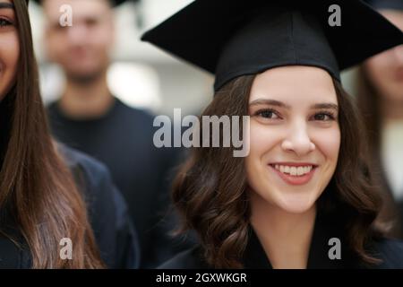 Istruzione, graduazione e concetto di persone - gruppo di felice gli studenti internazionali in mortaio e schede di corso di laurea gli abiti con diplomi Foto Stock