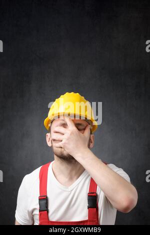 Deluso lavoratore edile in giallo elmetto, che copre il volto Foto Stock