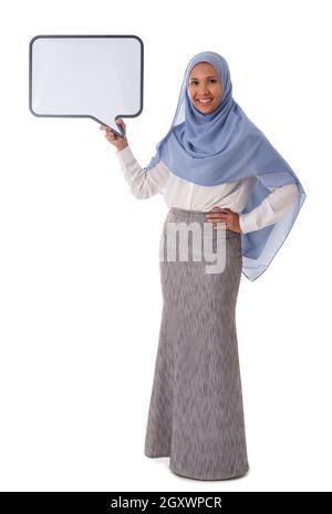 Piena dimensione di giovane ragazza musulmana asiatica felice indossando hijab tenendo cartella bianca per il testo, isolato sfondo bianco Foto Stock