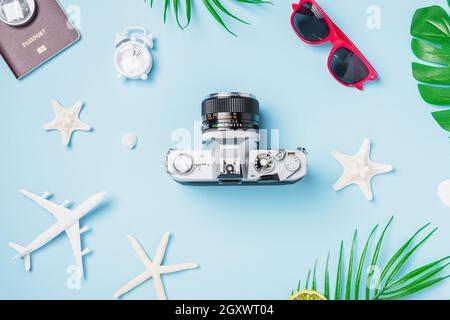 Flat Lay top view mockup retro fotocamera film, aereo, passaporto, stelle marine, conchiglie viaggiatore tropicale accessori su uno sfondo blu con spazio copia, Foto Stock