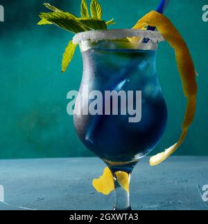 Cocktail Blue Lagoon con liquore blue curacao, vodka, succo di limone e soda, decorato con fetta di limone e foglie di menta. Foto Stock