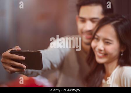 Cattura momenti luminosi. Felice ridere volti emotivi. Giovane amante posa per vacanza su sociale. Gioiosa giovane coppia amorevole che fa selfie su fotocamera w Foto Stock