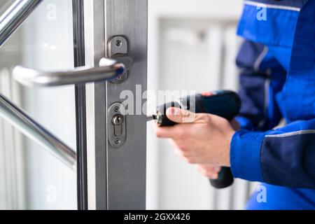 Fabbro uomo riparazione e sostituzione della serratura di metallo della porta Foto Stock