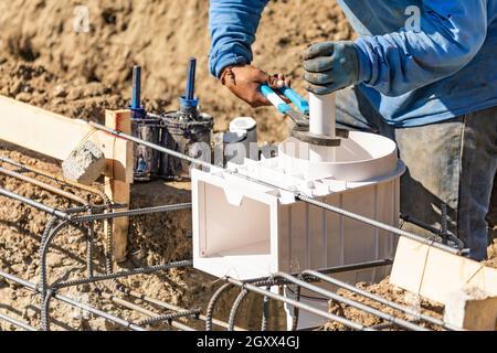 L'idraulico usando la chiave per installare il tubo in PVC al sito in costruzione. Foto Stock
