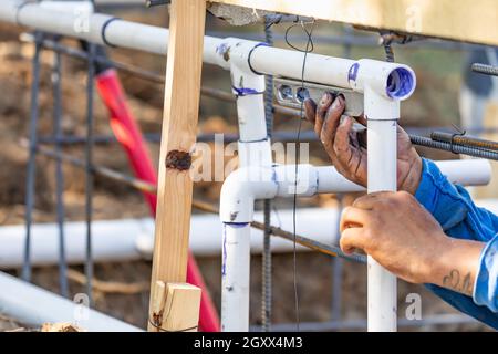 Plumber utilizza il livello mentre si installa il tubo in PVC al sito in costruzione. Foto Stock