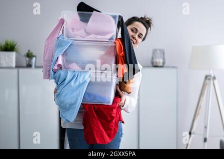 Donna decluttering e facendo lavanderia a casa Foto Stock