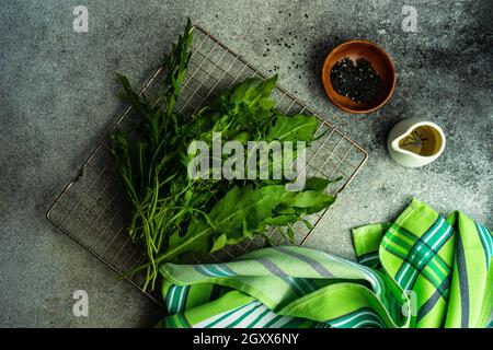 Foglie fresche di razzo organico su una griglia di raffreddamento con olio d'oliva e semi di sesamo nero Foto Stock