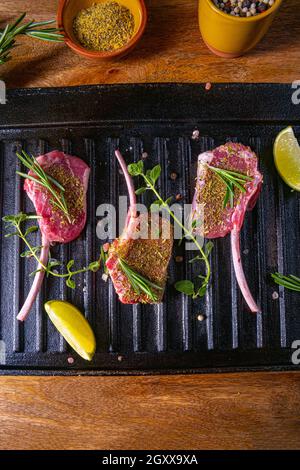 Costolette di agnello crudo condite e marinate con erbe Foto Stock