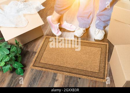 L uomo e la donna in piedi vicino a vuoto tappeto di benvenuto, scatole in movimento e di impianto. Foto Stock