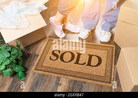 L uomo e la donna in piedi vicino a venduti tappeto di benvenuto, scatole in movimento e di impianto. Foto Stock