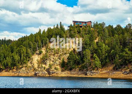 Casa in cima a una piccola montagna di pini accanto all'acqua Foto Stock