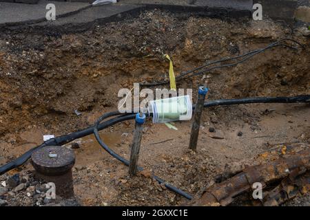 Scavato il marciapiede rivelando i fili in tubi di protezione. Costruzione di linee elettriche o cavi per telecomunicazioni, costruzione di rete ottica informaz Foto Stock