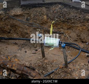 Scavato il marciapiede rivelando i fili in tubi di protezione. Costruzione di linee elettriche o cavi per telecomunicazioni, costruzione di rete ottica informaz Foto Stock