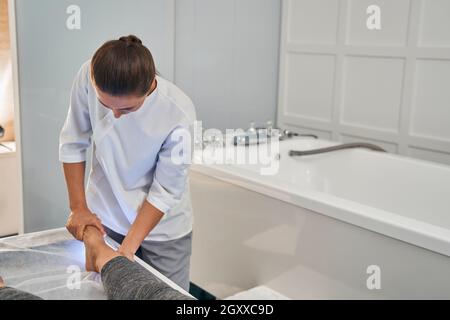 Foto focalizzata sull'osteopata che fa massaggio di riabilitazione Foto Stock