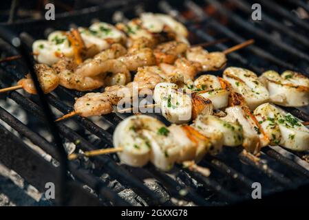 Spiedini di pesce con gamberi e calamari sulla griglia Foto Stock