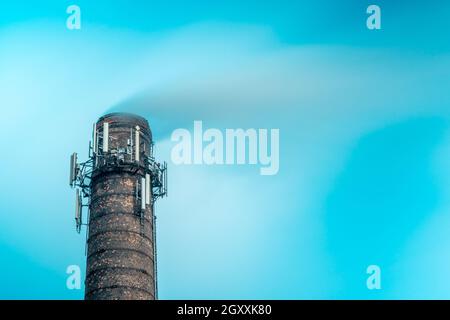 Alto camino industriale con antenne multiple. Fabbrica camino e vapore a lunga esposizione Foto Stock