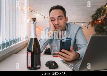 Uomo d'affari in camicia blu addormentato al lavoro con una bottiglia di alcol, ha dormito perché notte stormy festa con bevanda dopo l'azienda il 1 gennaio celebrato Foto Stock