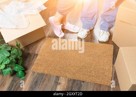 L uomo e la donna in piedi vicino a Casa dolce casa tappeto di benvenuto, scatole in movimento e di impianto. Foto Stock