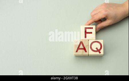 Iscrizione FAQ (domande frequenti) su blocchi di legno su sfondo grigio. Concetto di QA, guida e suggerimenti, maniglie per cubi, spazio di copia Foto Stock