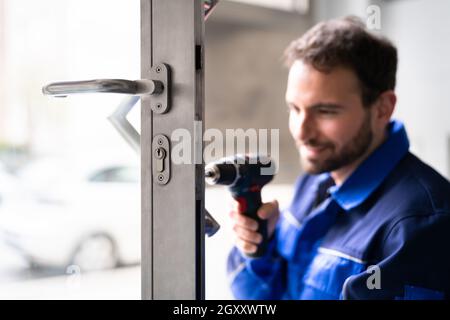 Fabbro uomo riparazione e sostituzione della serratura di metallo della porta Foto Stock