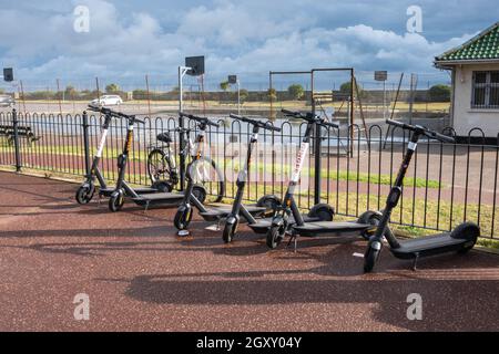 Una fila di scooter elettrici Ginger a noleggio sul lungomare di Great Yarmouth Foto Stock