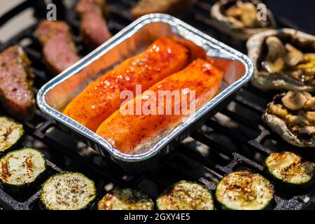 carne di vitello, salmone e zucchine su griglia da giardino con carbone Foto Stock