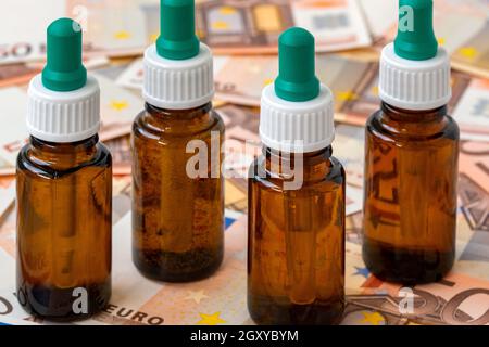 Immagine simbolica per costi elevati di farmaci con bottiglia di farmaco su denaro (banconote da 50 euro). Concetto medico. Foto Stock