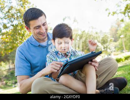 Felice il Padre e il figlio a giocare su un computer Tablet all'esterno. Foto Stock