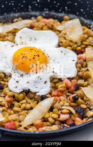 lenticchie con carne affumicata e cipolla servite con uova fritte Foto Stock