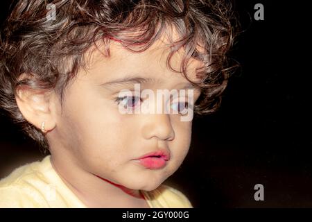 Primo piano volto foto di bella cute poco indù cute bambino indiano con nero e basso chiave sfondo creativo Foto Stock
