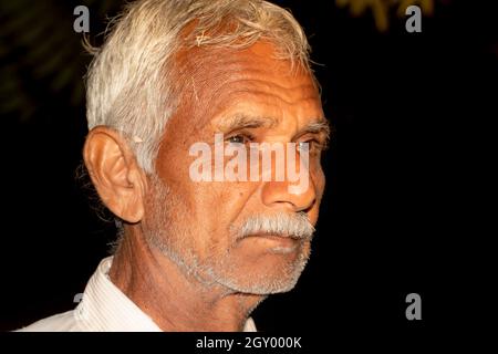 Primo piano faccia foto di bella cute senior indù cute indiano uomo agricolo invecchiato con nero e basso chiave sfondo creativo Foto Stock