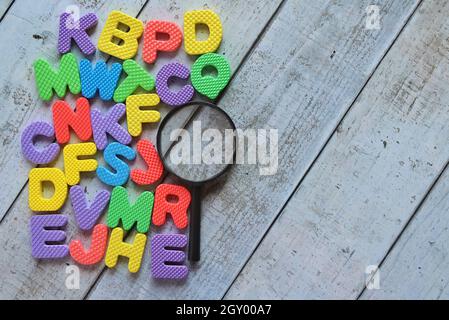 Vista dall'alto della lente d'ingrandimento e dell'alfabeto colorato su un tavolo di legno. Spazio di copia per il testo. Foto Stock