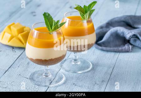 Cheesecake di Mango guarnito con menta servita nei bicchieri Foto Stock