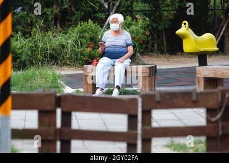 Taipei, Taipei, Taiwan. 6 ottobre 2021. Una signora anziana con una maschera attende riposa in un'area seduta fuori a Taipei, dopo il 7° giorno consecutivo con zero casi locali di Covid segnalati. Secondo il CDC di Taiwan, con il governo che mette a disposizione del pubblico un maggior numero di vaccini, tra cui AstraZeneca e BionTech, sono state abolite misure di contenimento più numerose. (Credit Image: © Daniel Ceng Shou-Yi/ZUMA Press Wire) Foto Stock