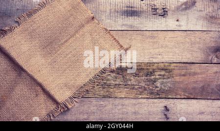 pezzo di tela con bordi strappati su uno sfondo di tavole di legno grigio, vista dall'alto Foto Stock