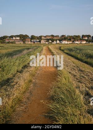 Tornando a piedi dalla spiaggia a Cley accanto al villaggio di mare lungo il sentiero rialzato attraverso la riserva naturale di Cley Marshes Norfolk Inghilterra UK Foto Stock