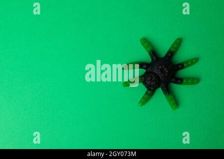 Caramelle gommose sotto forma di ragno su sfondo verde. Foto Stock