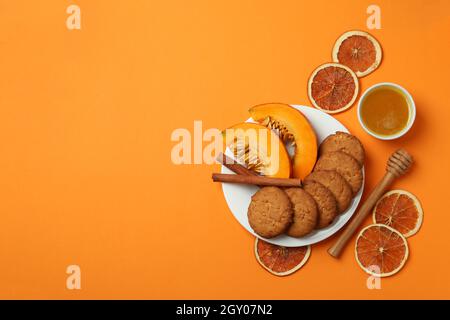 Concetto di cibo gustoso con biscotti di zucca su sfondo arancione. Foto Stock