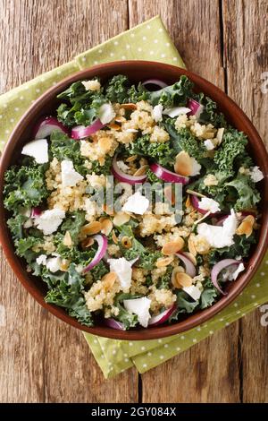 Insalata di quinoa con cipolle, kale, feta e mandorle da vicino in una ciotola sul tavolo. Vista dall'alto verticale Foto Stock