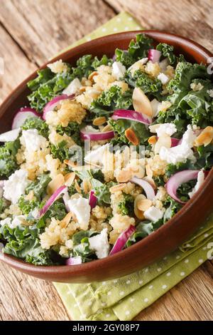 Insalata di quinoa con cipolle, kale, feta e mandorle da vicino in una ciotola sul tavolo. Verticale Foto Stock