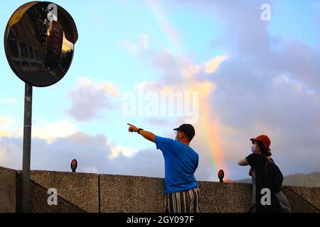 Taipei, Taipei, Taiwan. 6 ottobre 2021. Le persone con maschere per il viso godono della vista di un arcobaleno in una zona residenziale di Taipei, dopo il 7° giorno consecutivo con zero casi locali Covid segnalati. Secondo il CDC di Taiwan, con il governo che mette a disposizione del pubblico un maggior numero di vaccini, tra cui AstraZeneca e BionTech, sono state abolite misure di contenimento più numerose. (Credit Image: © Daniel Ceng Shou-Yi/ZUMA Press Wire) Foto Stock