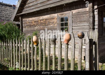 Pentole per una stufa a legna rustica, asciugate su una palisata rustica in legno. Sullo sfondo di una vecchia casa di legno. Foto Stock