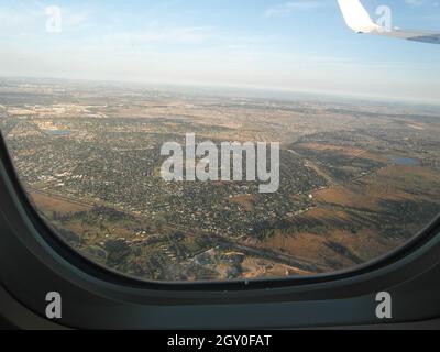 Vista da una finestra di un aereo su un sobborgo della città in avvicinamento all'aeroporto Foto Stock