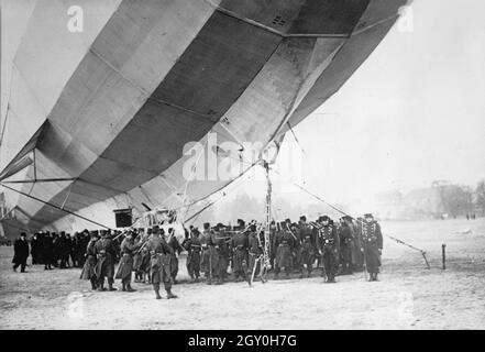 Foto d'epoca 3 aprile 1913 di un veliero tedesco, classe H Zeppelin IV, o LZ 16, che ha fatto un atterraggio d'emergenza sul terreno della sfilata di Luneville, Francia dopo aver corso a basso consumo di carburante. I soldati francesi si riuniscono intorno al veliero Foto Stock