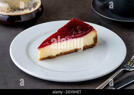 Cheesecake al lampone con caffè da caffè su tavola in pietra nera Foto Stock