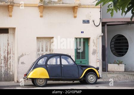 Vintage Citroen 2CV, nero e giallo a colori parcheggiato su strada fuori casa in villaggio in Francia Foto Stock