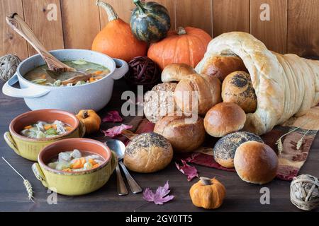 Primo piano di una cornucopia di pane con panini che si versano e ciotole di zuppa di tacchino, pronti per mangiare. Foto Stock