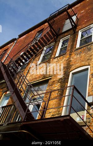 I gradini di fuga del fuoco nero salgono su un edificio in mattoni con molte finestre Foto Stock