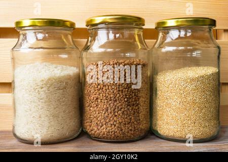 Vasetti di vetro di cereali riso grano saraceno quinoa per cucinare cibi sani in vasetti di vetro su scaffale di legno Foto Stock