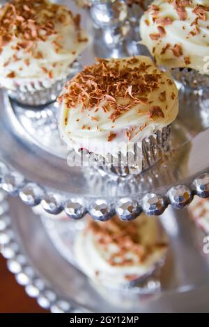 Cupcake con glassa bianca e guarnizione al cioccolato su un piatto decorativo in argento Foto Stock